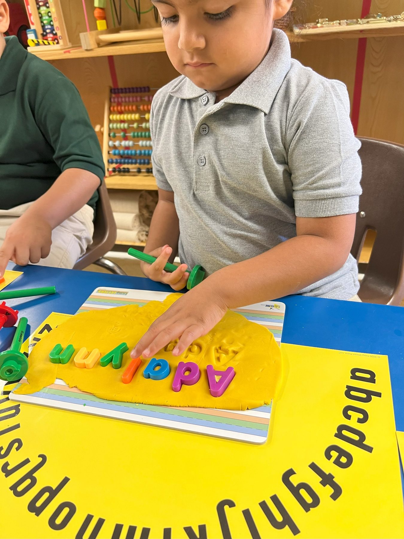 A young child practicing letters or writing at Alvani Academy