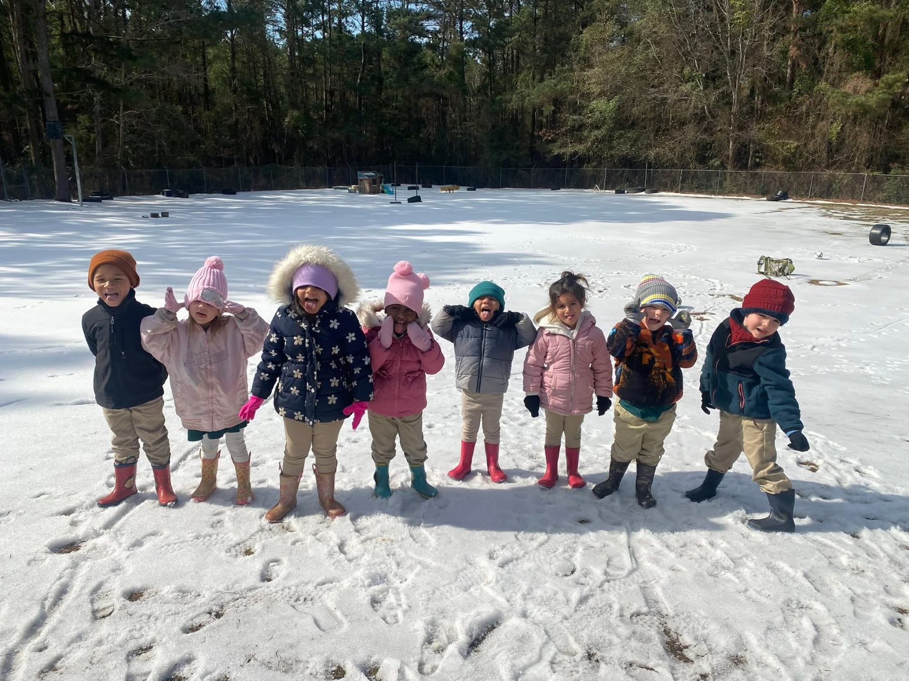 Children bundled up and enjoying outdoor play at Alvani Academy during a seasonal activity
