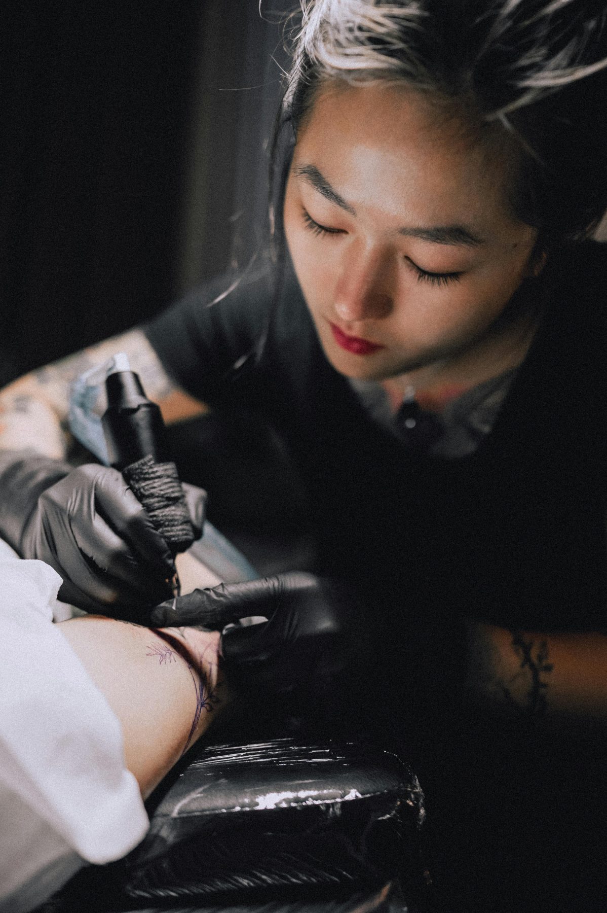 Mara Vale, a Gilded Moth tattoo artist specializing in fine line, botanical, and script tattoos